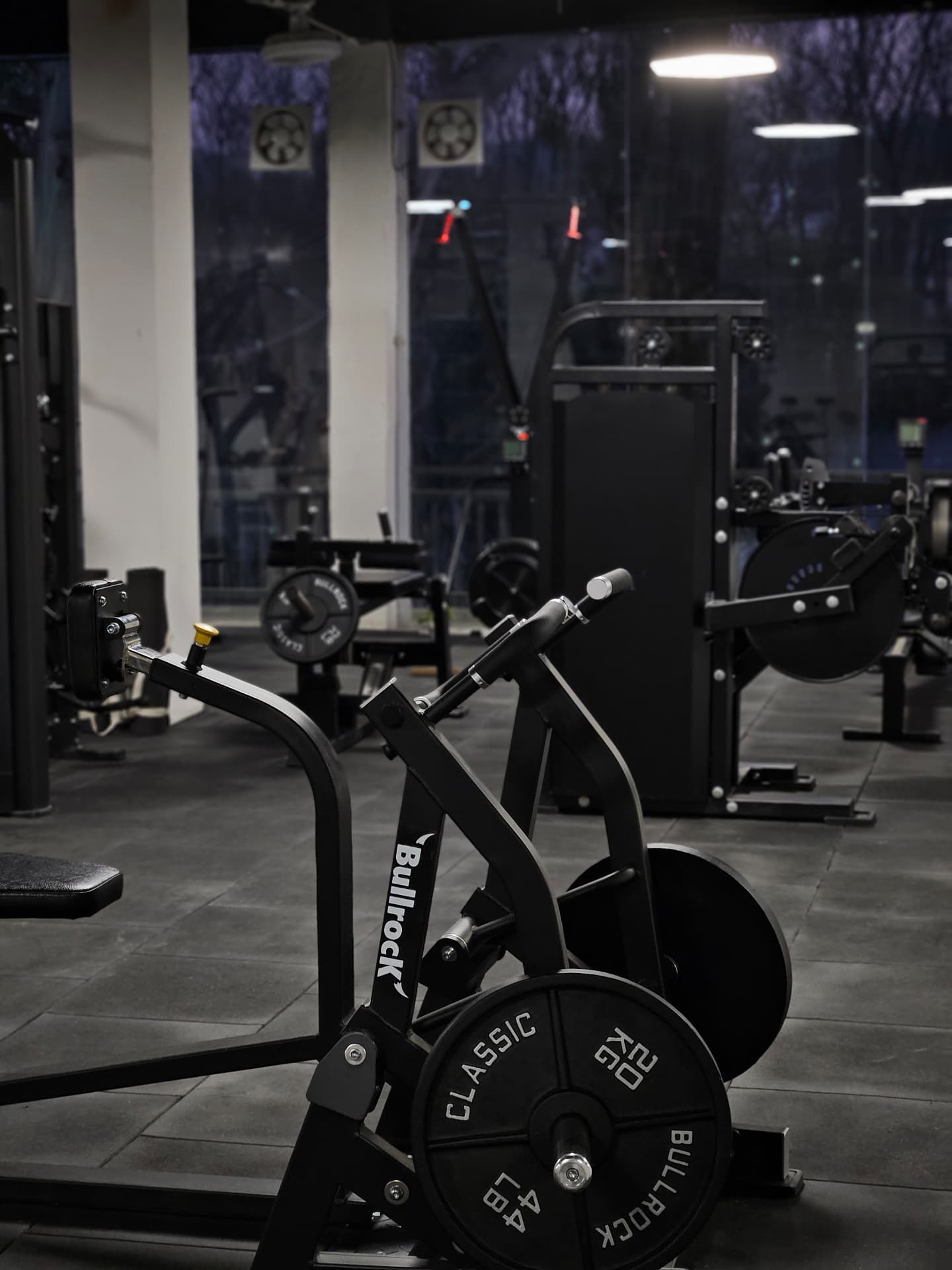 The Monochrome Gym training floor with mid-row machine, plate-loaded machines and toughened glass windows